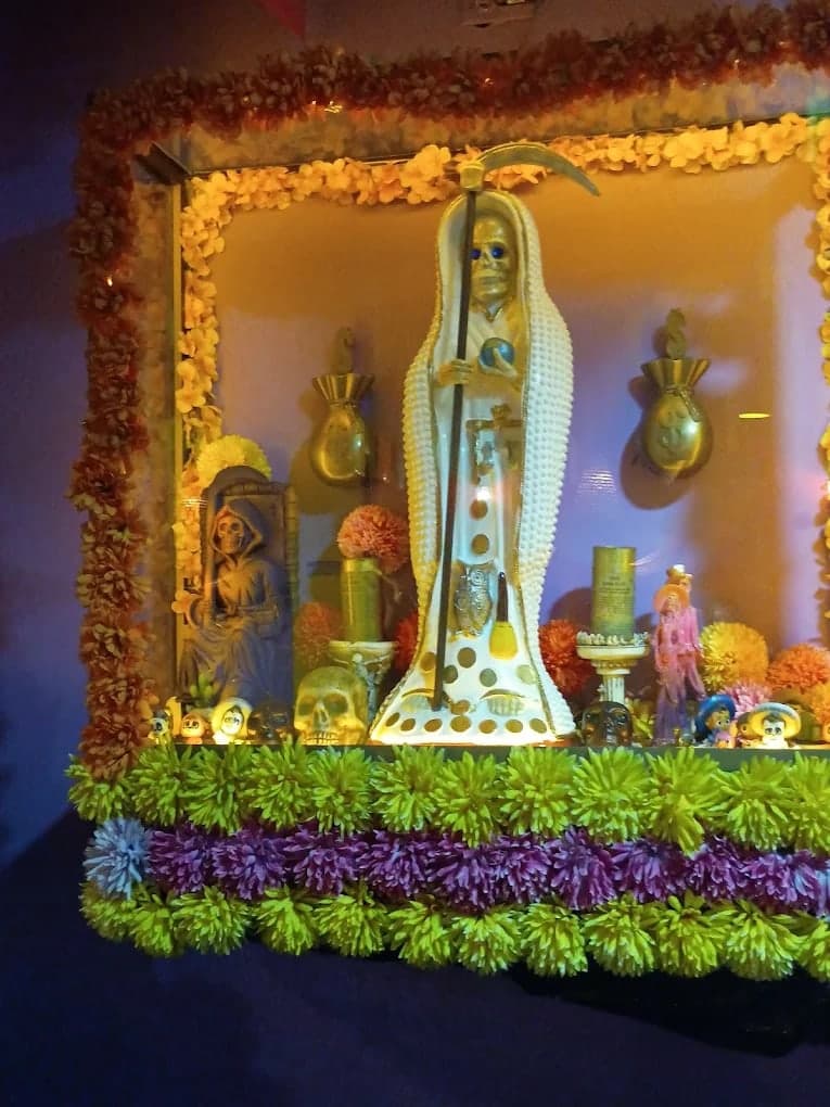 Altar del local con una figura de la Santa Muerte rodeada de flores
